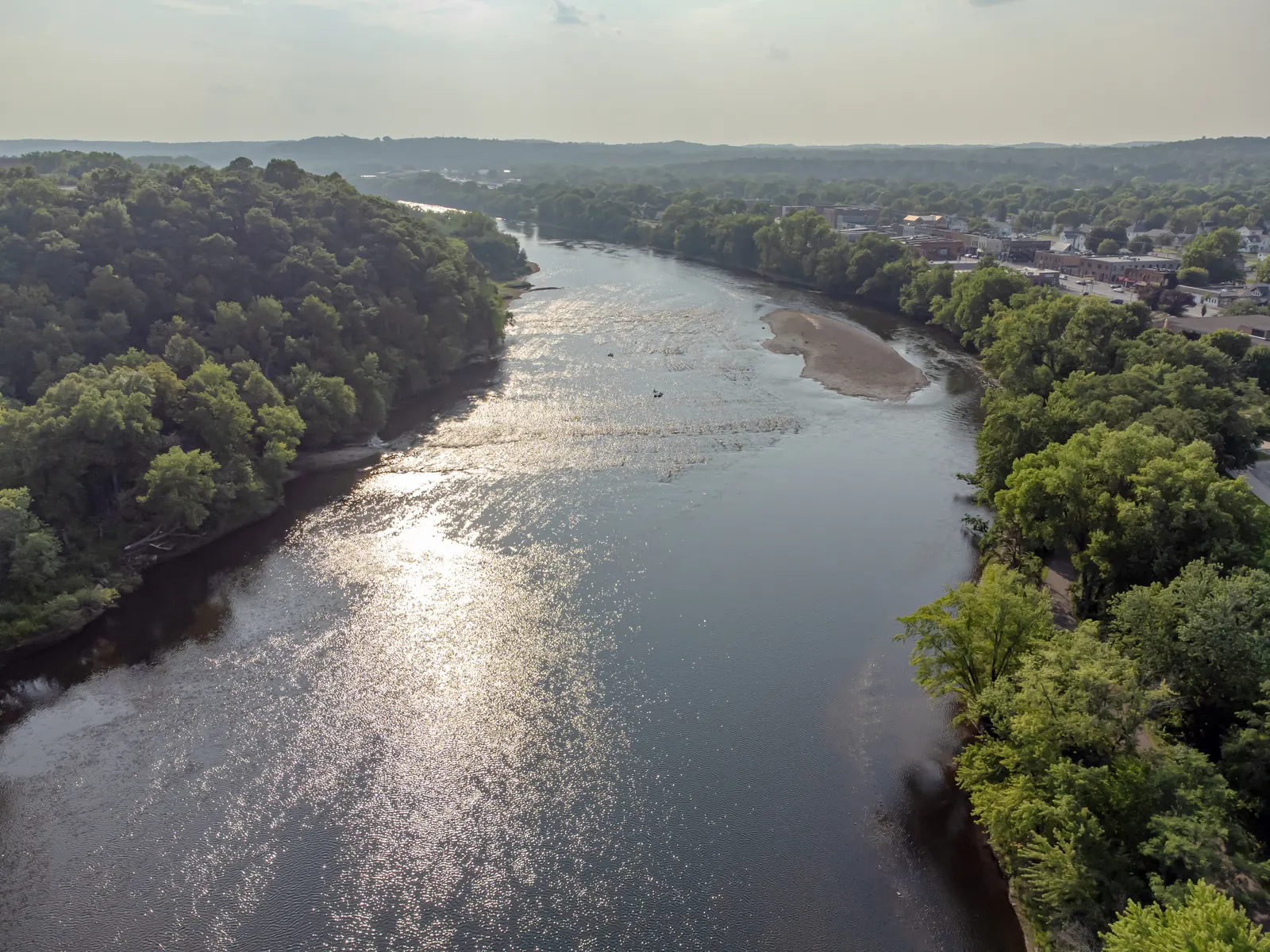 The Chippewa River winds through a broad grassy corridor under a bright sky.