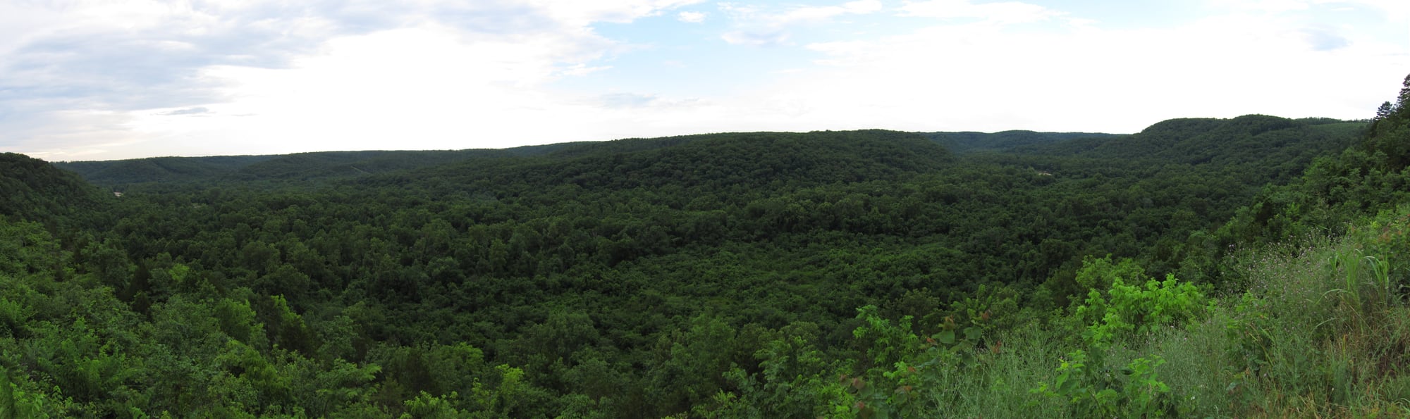 The Jacks Fork River winds below wooded Ozark hills with a gravel bar along the clear channel.