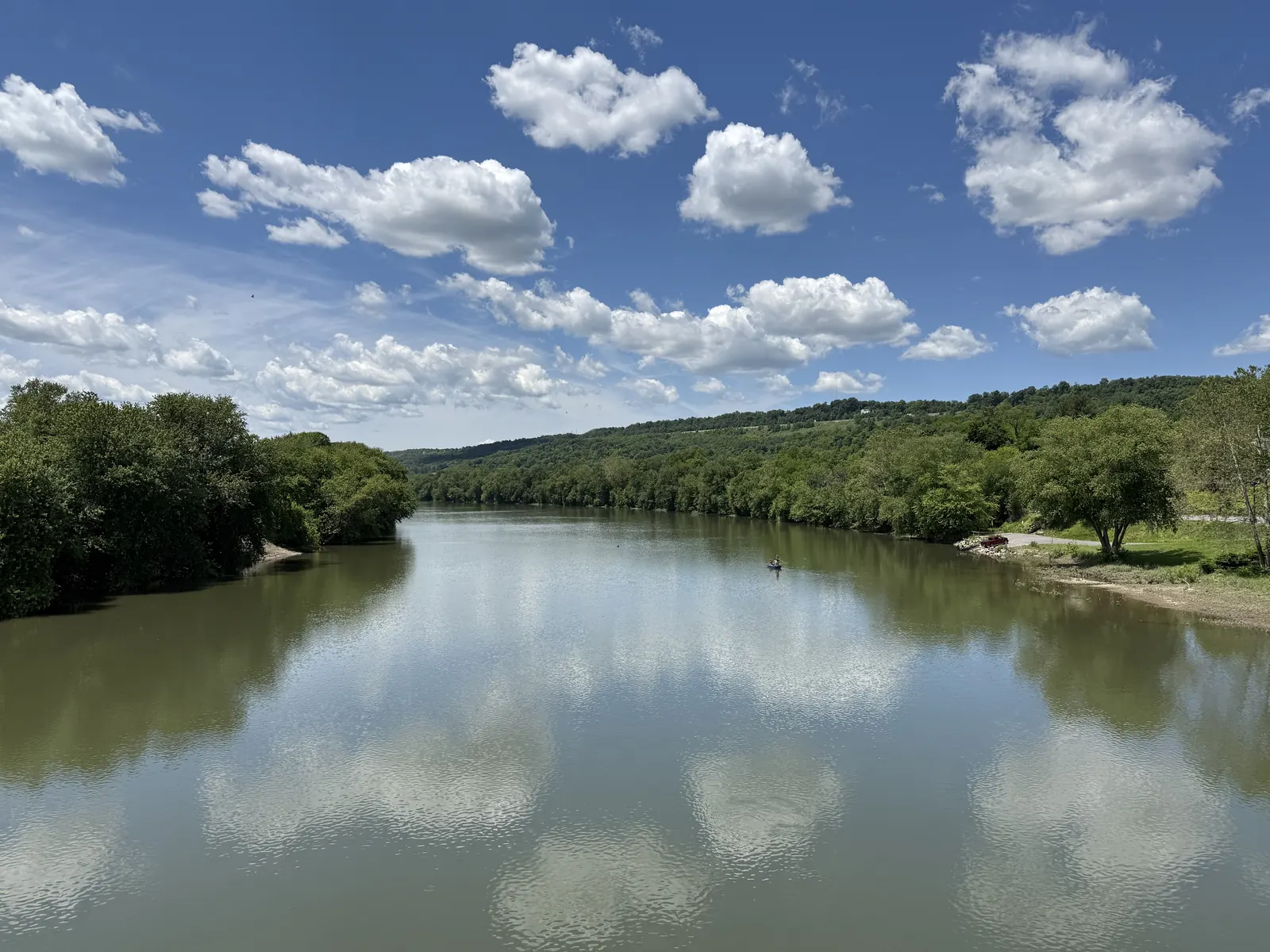 The Juniata River flows west of the Pennsylvania Route 103 bridge in Lewistown under a bright early-summer sky.