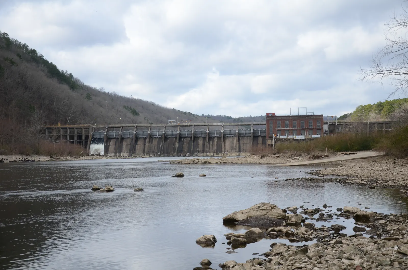 Remmel Dam spans the Ouachita River with release water below the concrete spillway and wooded banks nearby.