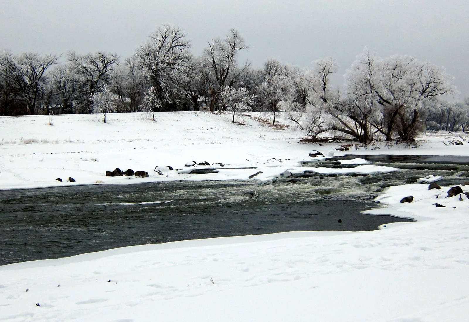 The Red River of the North curves through an urban winter landscape.