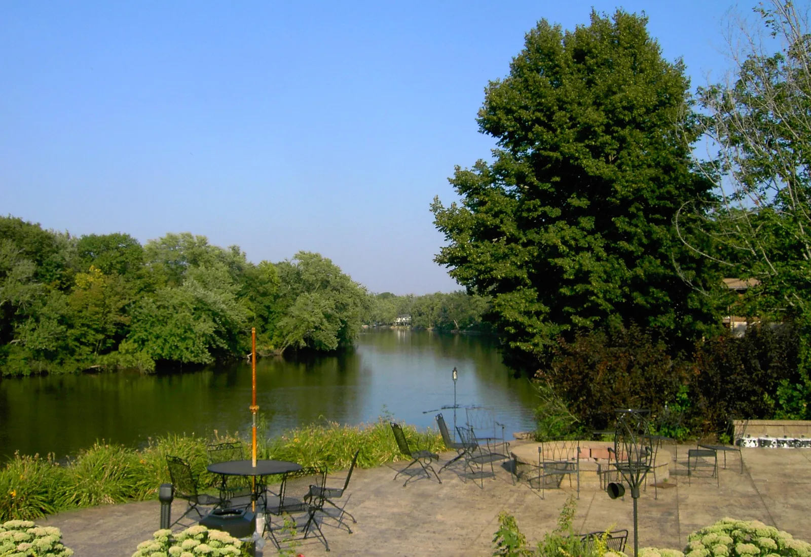 The Wapsipinicon River flows past a tree-lined bank in Independence, Iowa.
