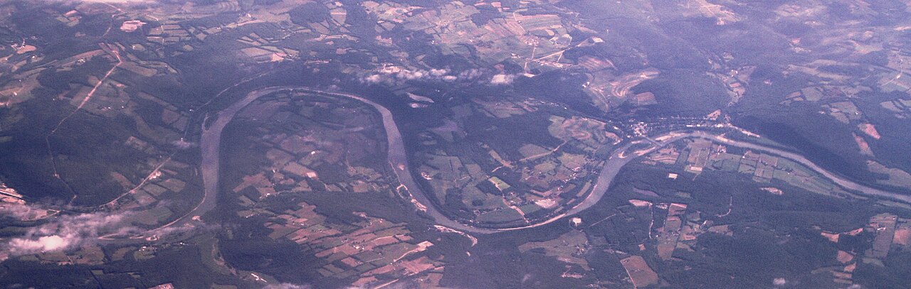 An aerial view shows the Susquehanna River bending through the Laceyville corridor with wooded banks and open Pennsylvania valley farmland.
