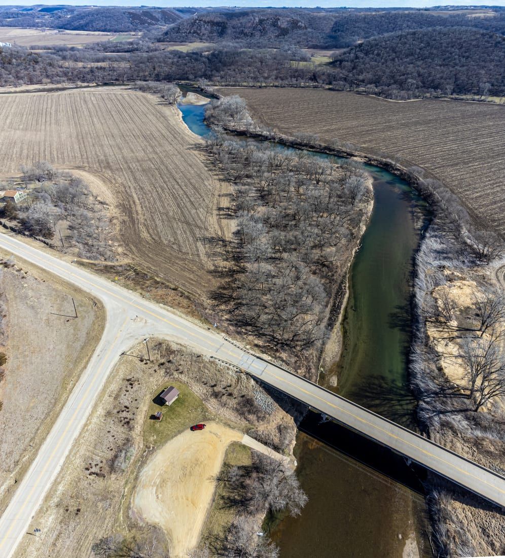 An aerial view looks down at the Upper Iowa River winding between wooded bluffs and farm fields.